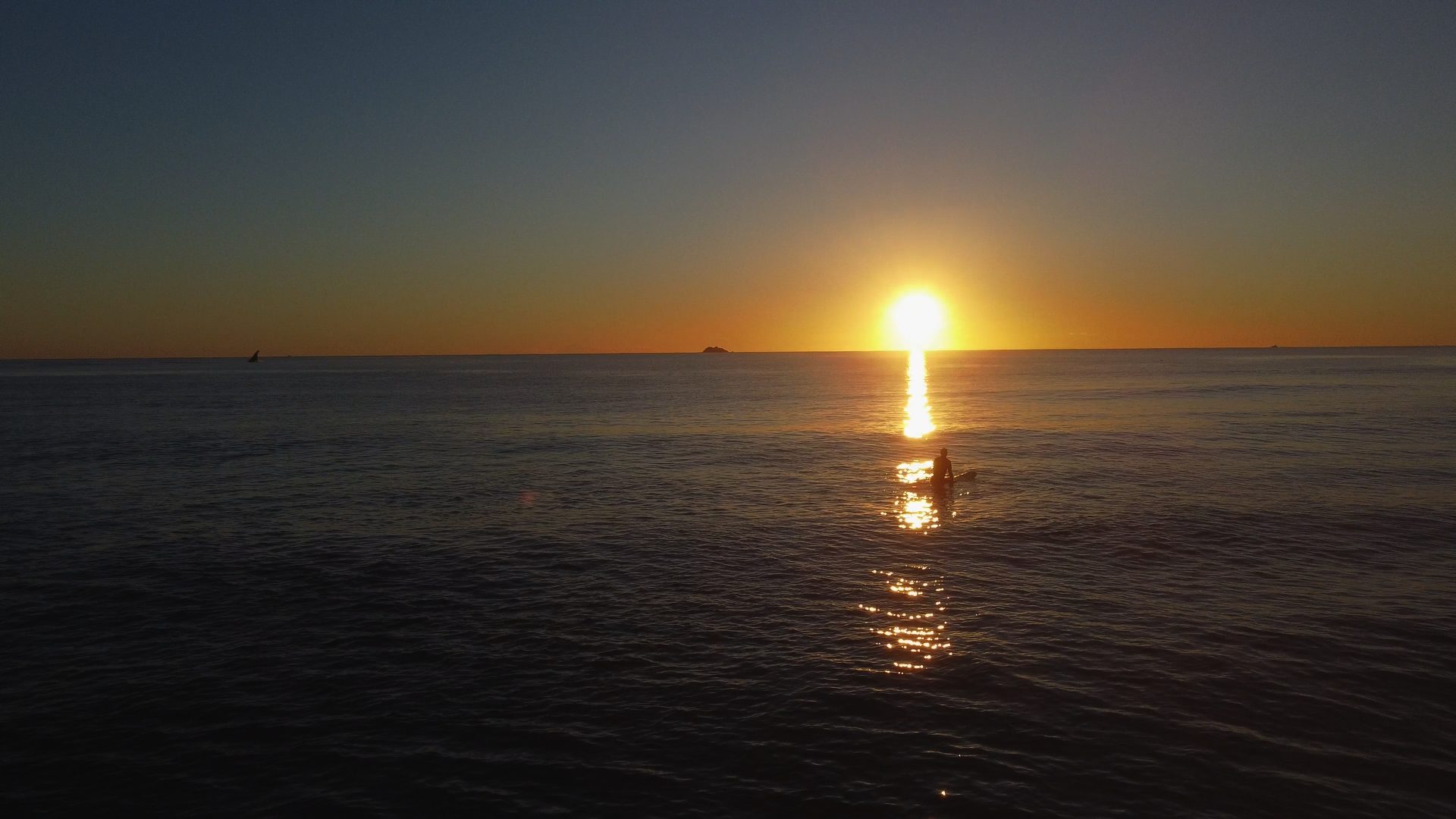 A surfer waiting on the water as the sun rises