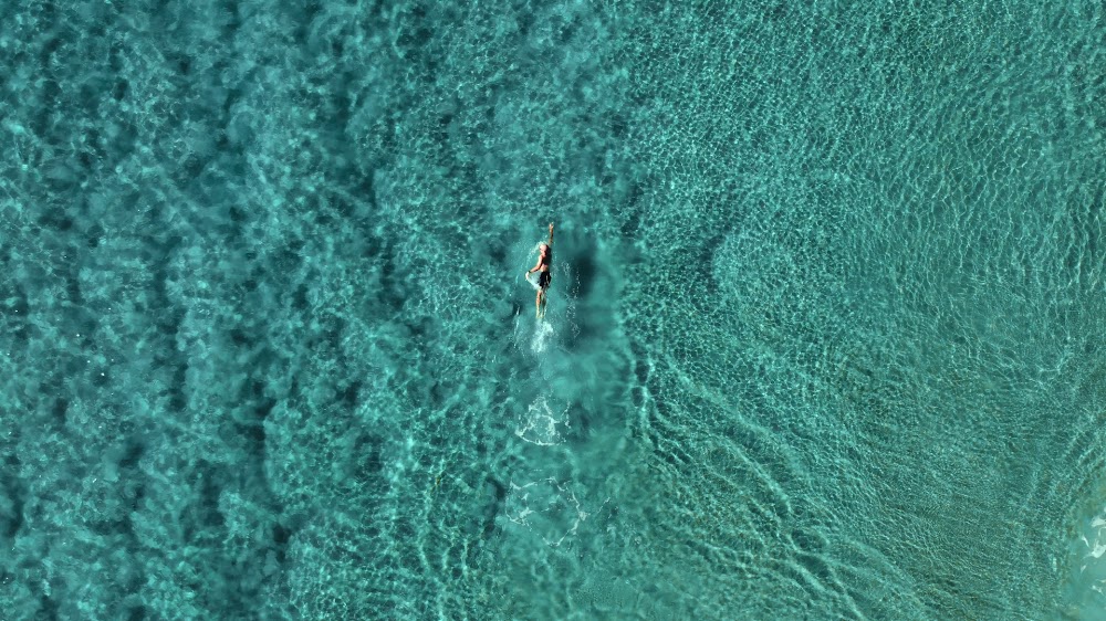 A swimmer seen from directly above in clear turquoise water